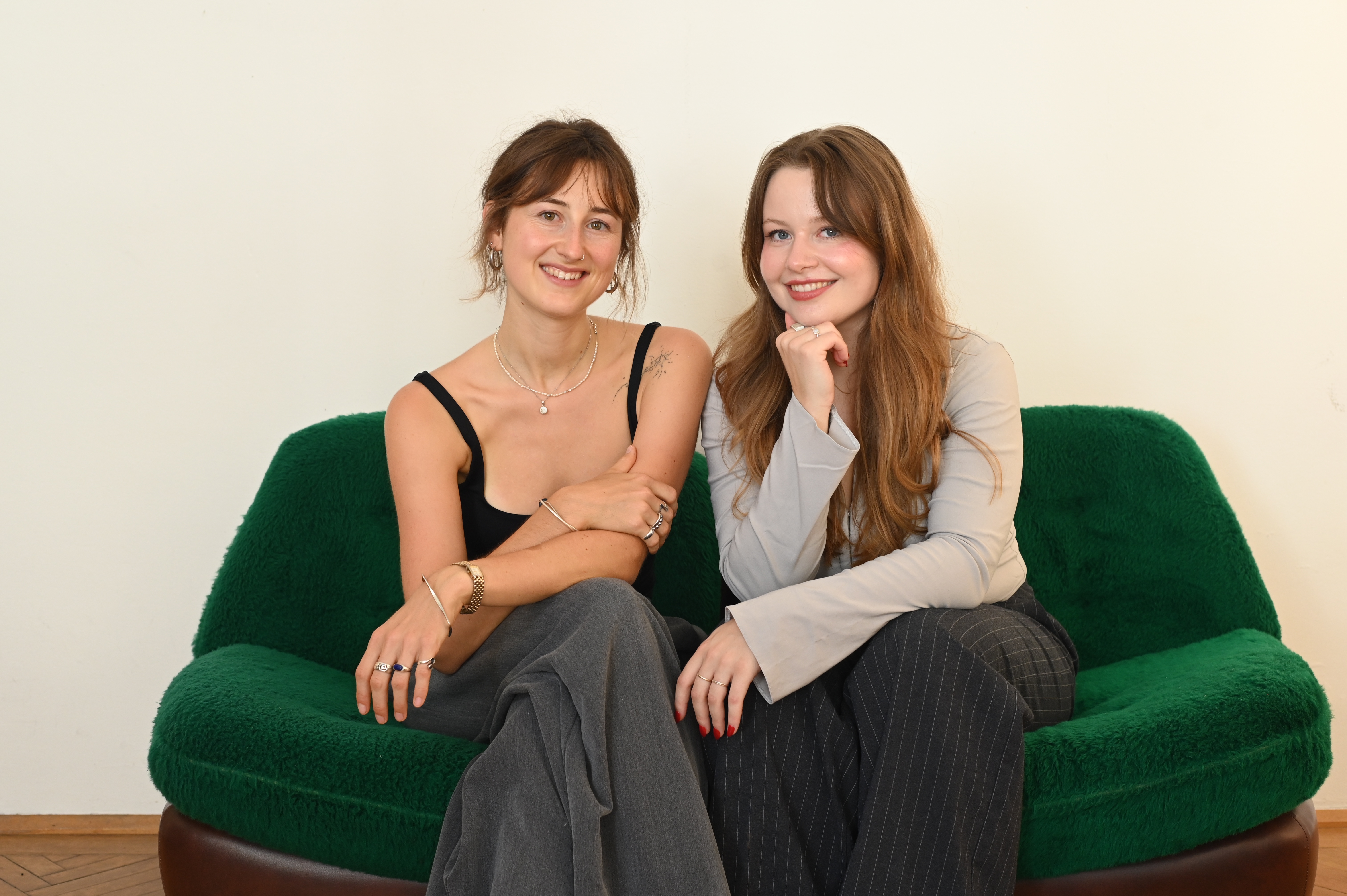 Paula Schlager und Fiona Warmdt sitzen nebeneinander auf einem grünen Samtsofa